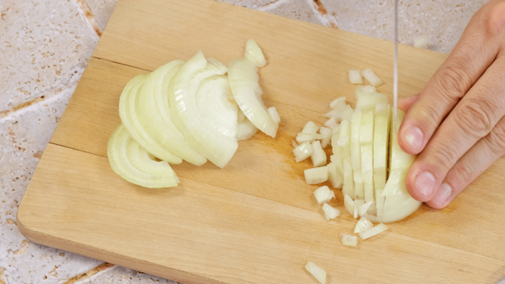 Eine helle Zwiebel wird in Würfel geschnitten.