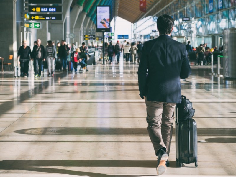 Ein GeschÃ¤ftsmann mit einem Koffer an einem Flughafen.