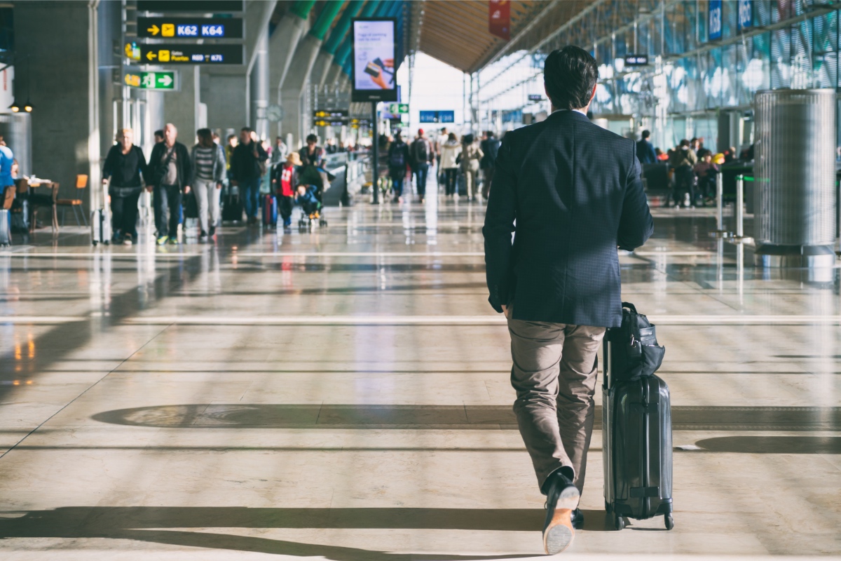 Ein GeschÃ¤ftsmann mit einem Koffer an einem Flughafen.