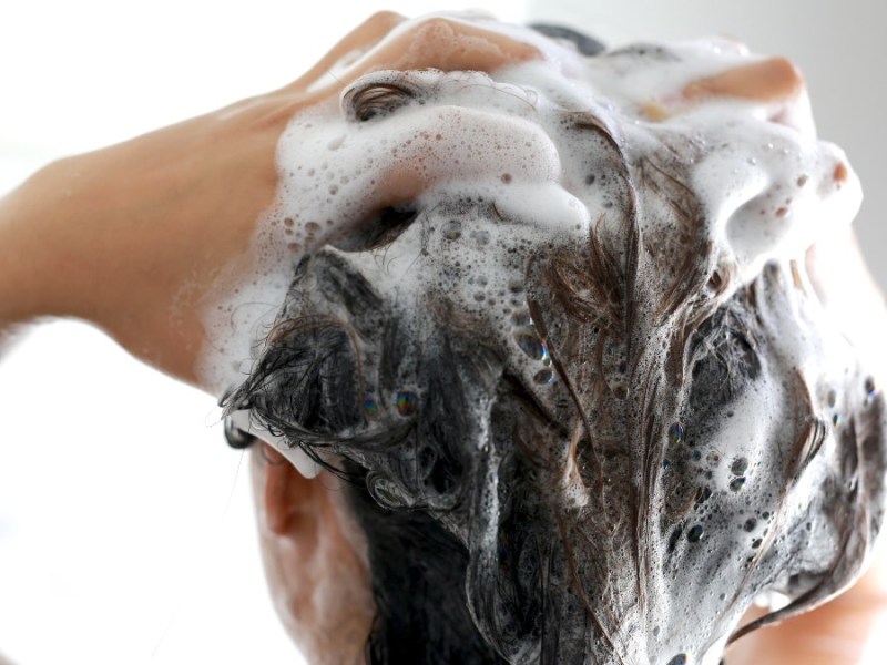 Eine Person schÃ¤umt seine Haare mit Shampoo ein.