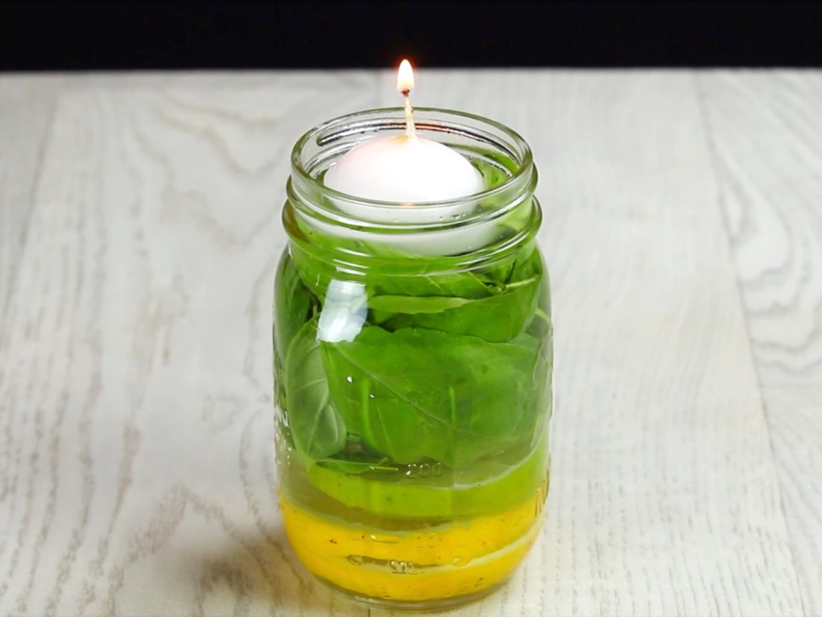 Eine selbstgemachte Mückenkerze aus Limette, Basilikum und Zitrone in einem Einmachglas.