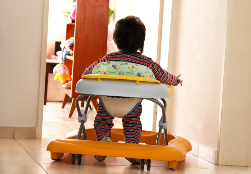 Ein Baby läuft in einem Gehfrei durch einen Wohnungsflur.