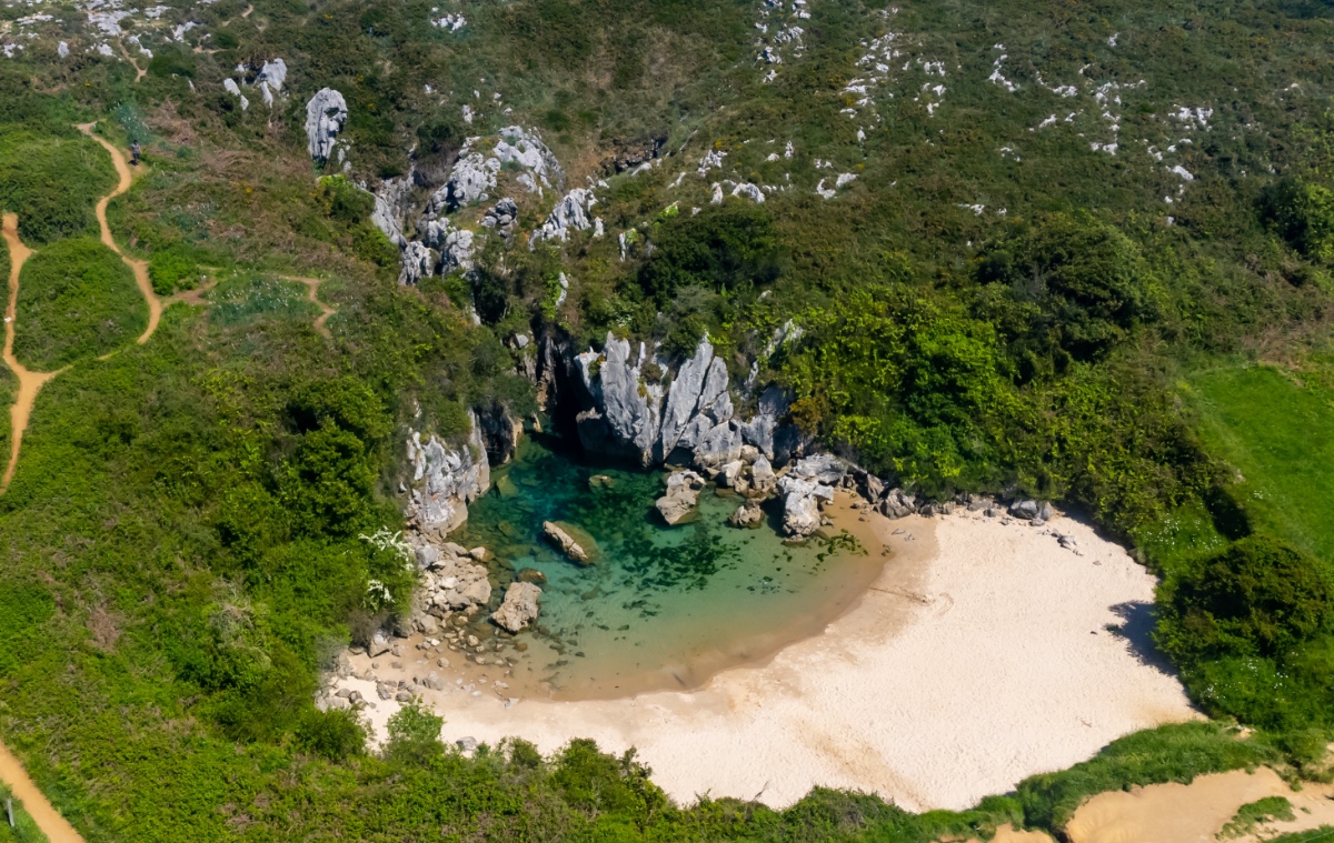 Ein Foto von einem kleinen Strand in einer Bucht, aus der Luft geschossen.