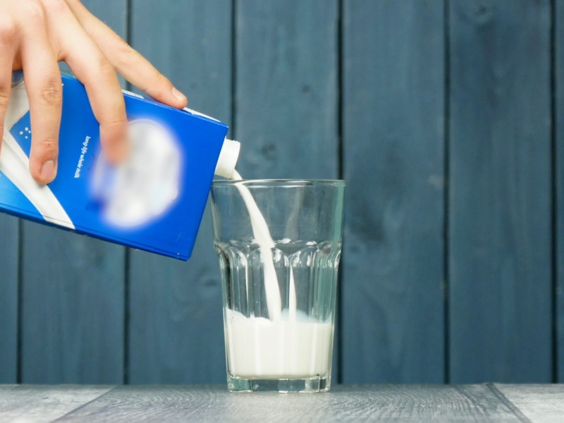 Milch wird aus einem Tetrapak in ein Glas gegossen.