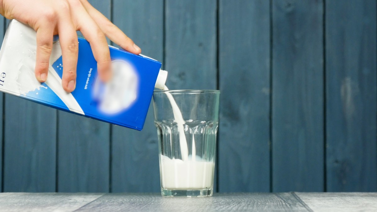 Milch wird aus einem Tetrapak in ein Glas gegossen.