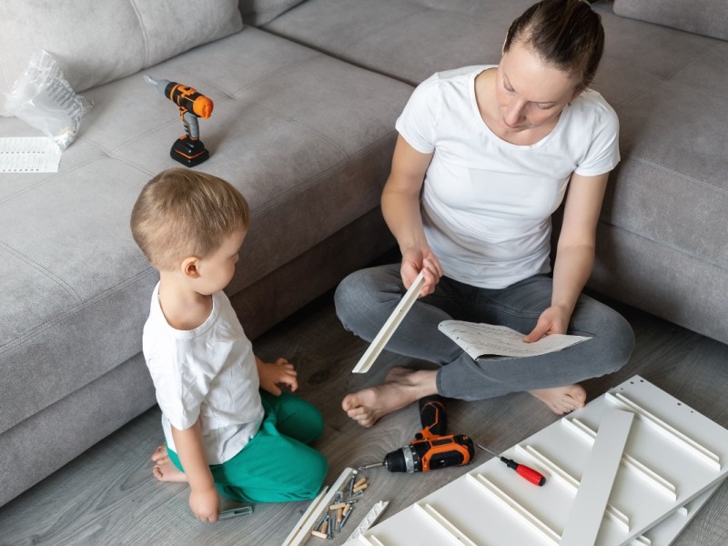 Eine Mutter baut mit ihrem Kind ein Möbelstück von IKEA auf.