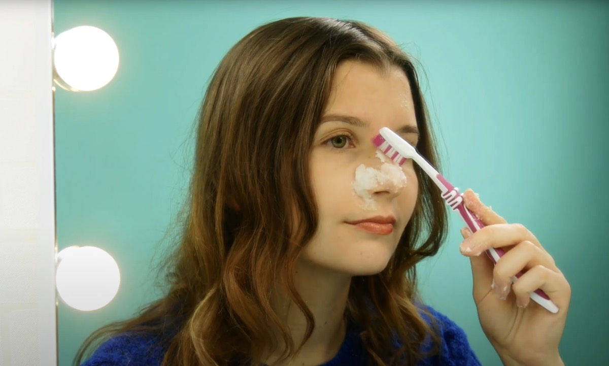 Eine junge Frau reinigt sich die Haut mit einem Backpulver-Peeling und einer ZahnbÃ¼rste.