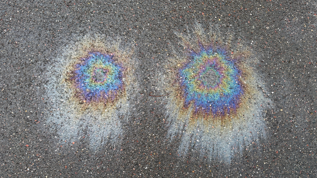 Zwei Ölflecken auf Asphalt.