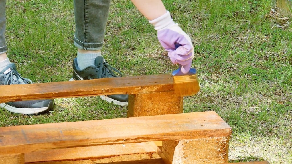 Europaletten werden mit Holzlasur überzogen.