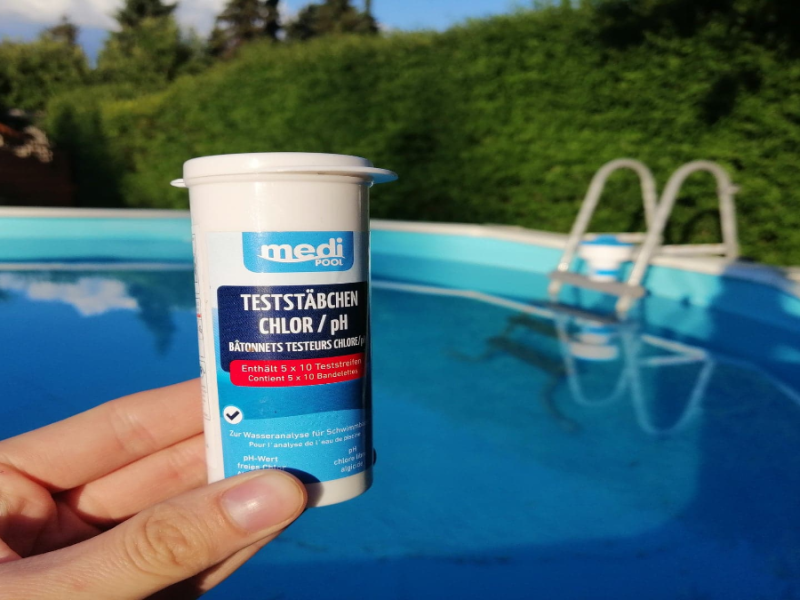 Eine Dose Chlor vor einem Pool.