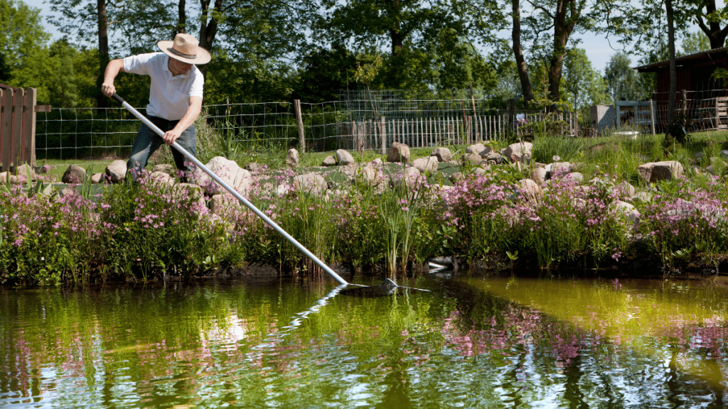 Ein Mann säubert einen Gartenteich.