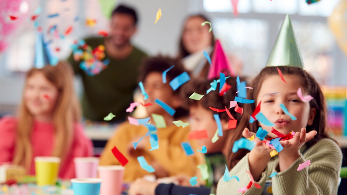 Kind pustet Konfetti am Geburtstag durch die Luft