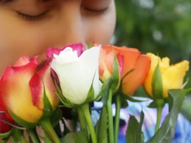 Eine junge Frau riecht an einem StrauÃŸ Rosen.