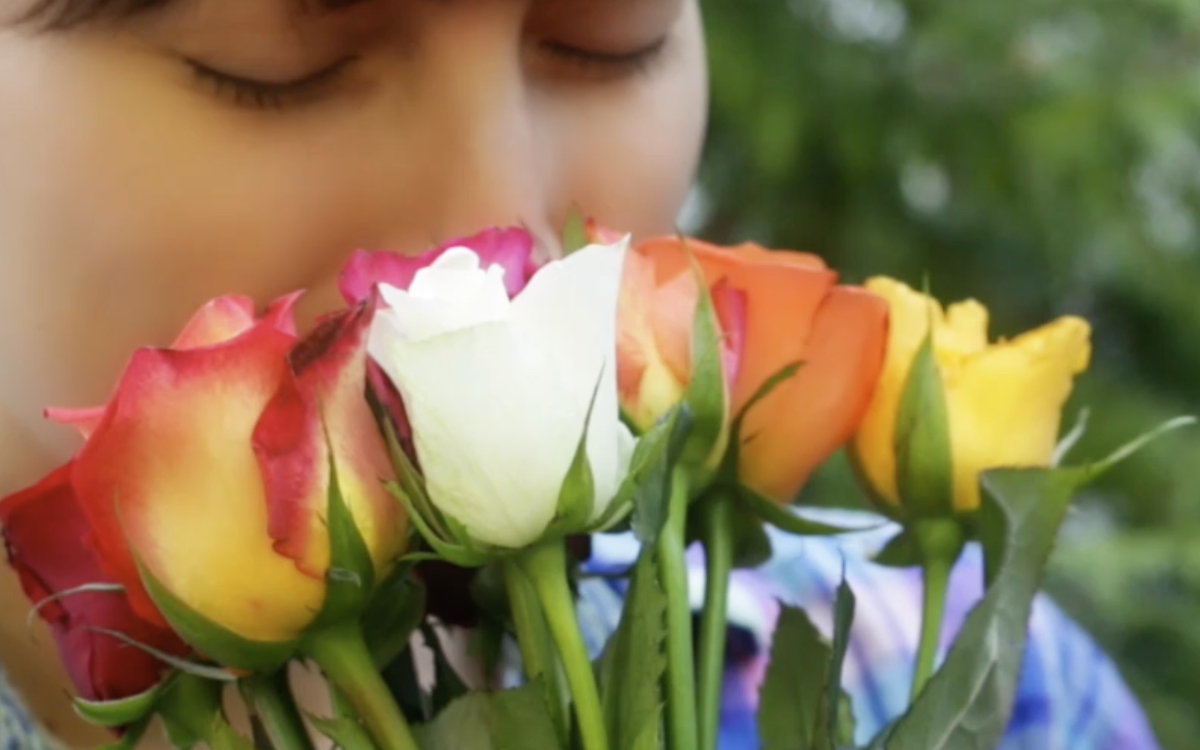 Eine junge Frau riecht an einem StrauÃŸ Rosen.