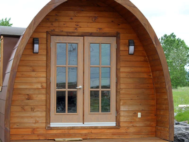 Ein Tiny House mit gewölbtem Dach in einem Garten.