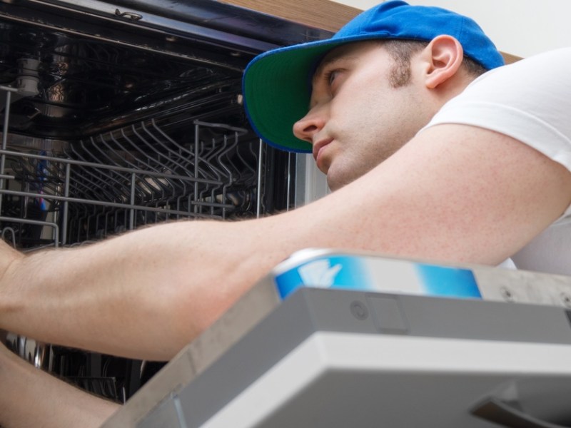 Handwerker repariert eine Spülmaschine.