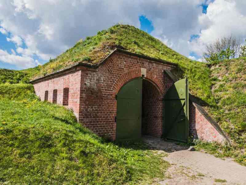 Ein mit Gras bewachsener Bunker aus Ziegelsteinen unter einem Hügel.