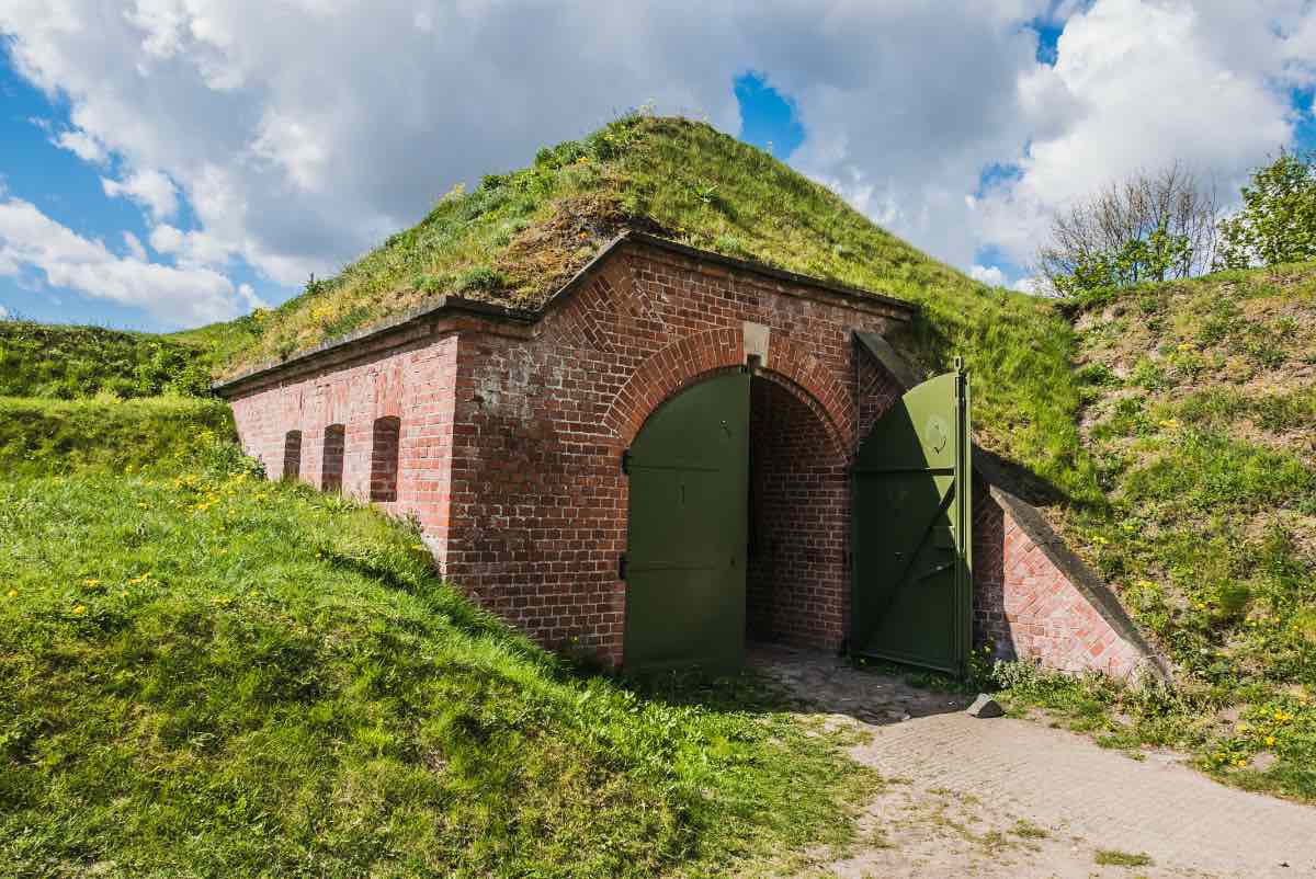 Ein mit Gras bewachsener Bunker aus Ziegelsteinen unter einem Hügel.