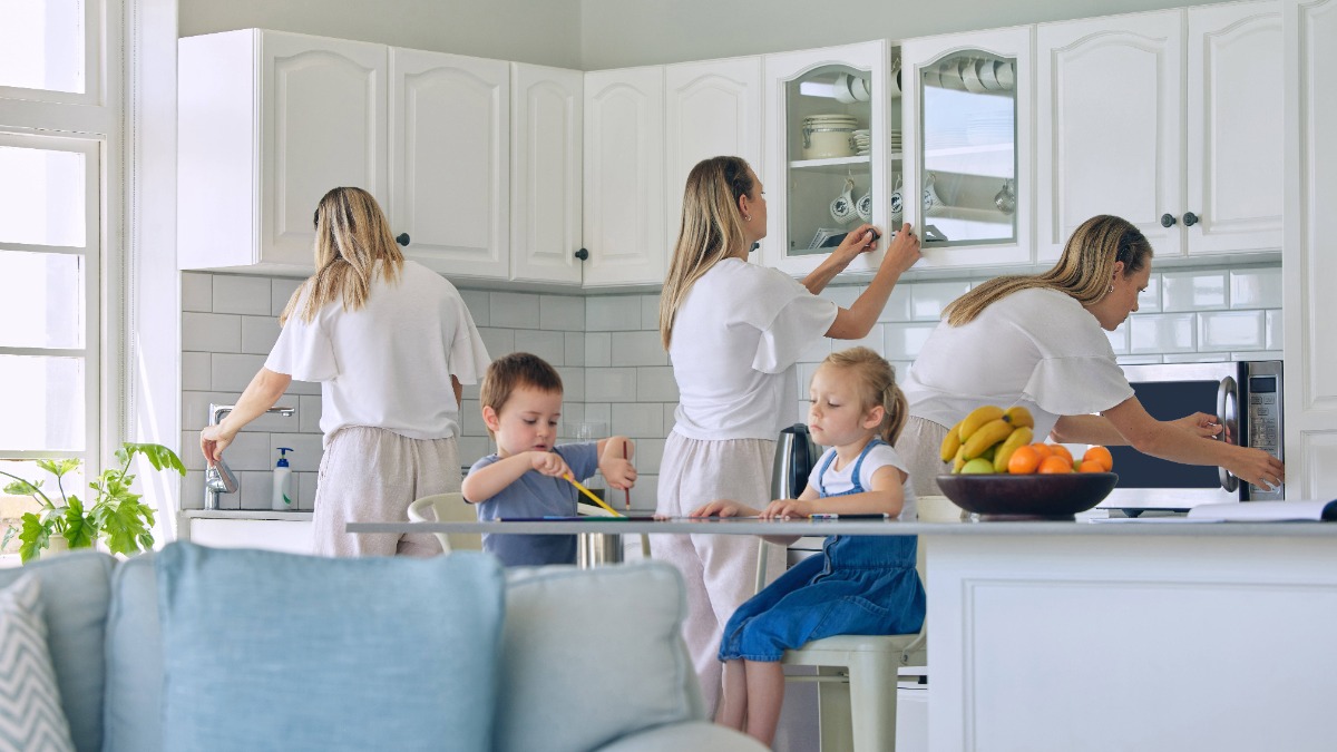 Mutter macht im Hintergrund Hausarbeit während die Kinder im Vordergrund essen