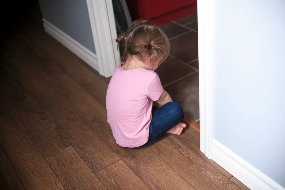 kleines Mädchen sitzt traurig auf dem Boden