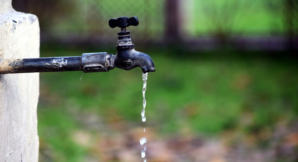 Ein tropfender Wasserhahn in einem Garten.