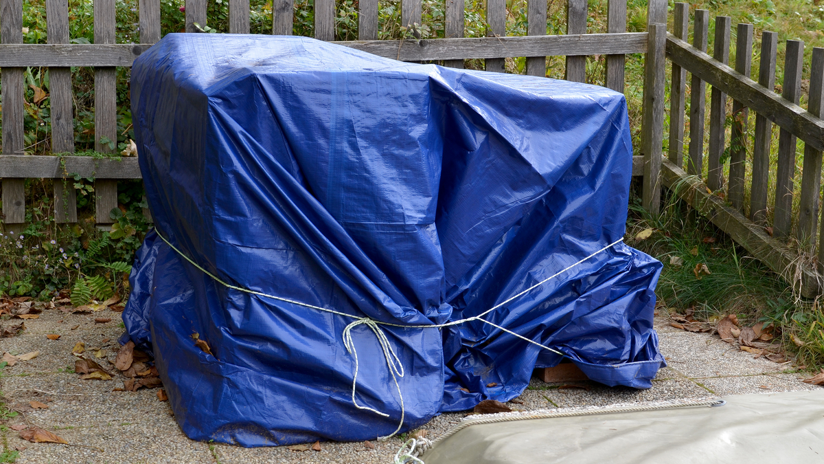 Gartenmöbel, die in blaue Plane eingepackt sind.