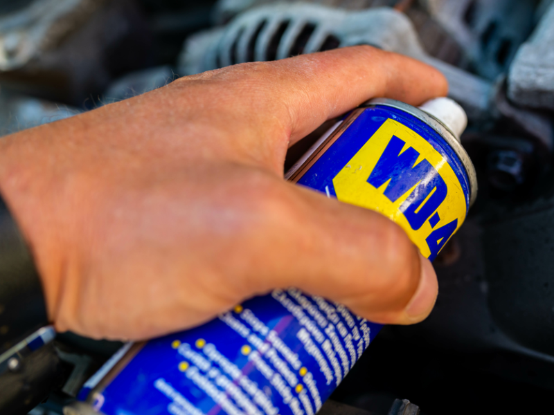 Eine Hand hÃ¤lt eine Dose WD-40 Ã¼ber eine verrostete Stelle