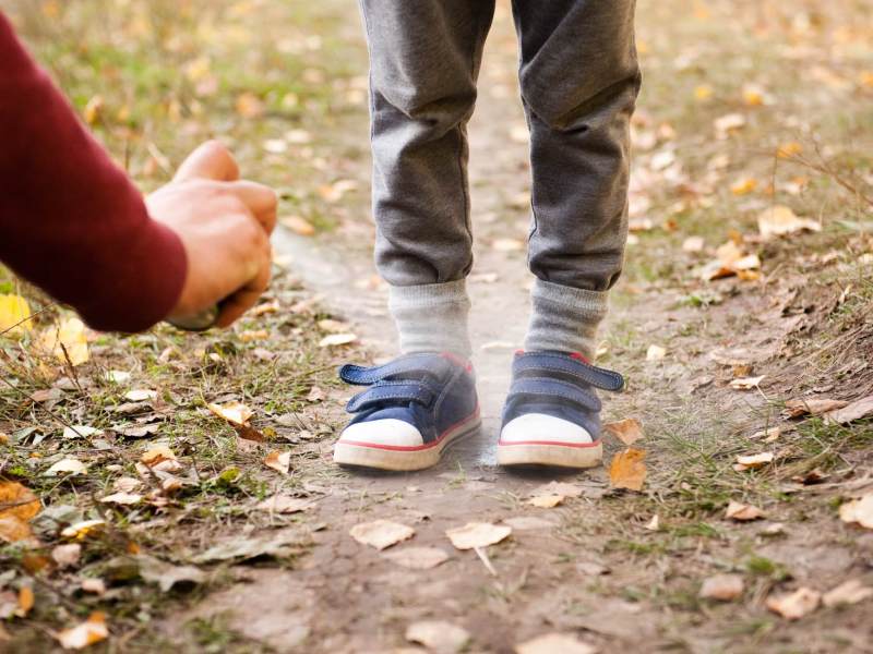 Die Schuhe eines Jungen werden mit Mückenspray eingesprüht.