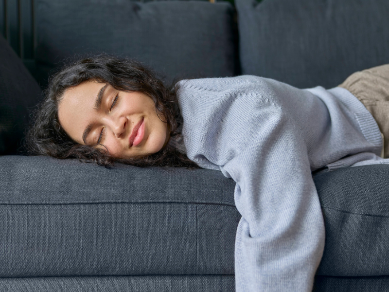 Eine Frau liegt in Bauchlage auf einem Sofa.