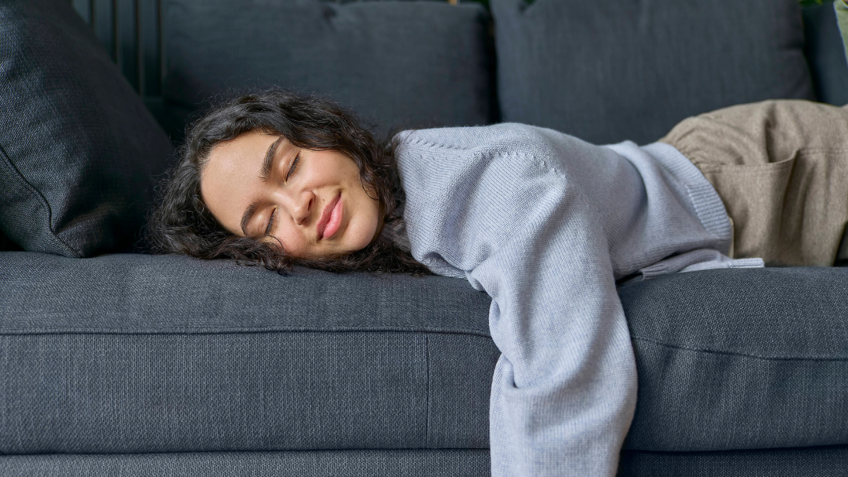 Eine Frau liegt in Bauchlage auf einem Sofa.