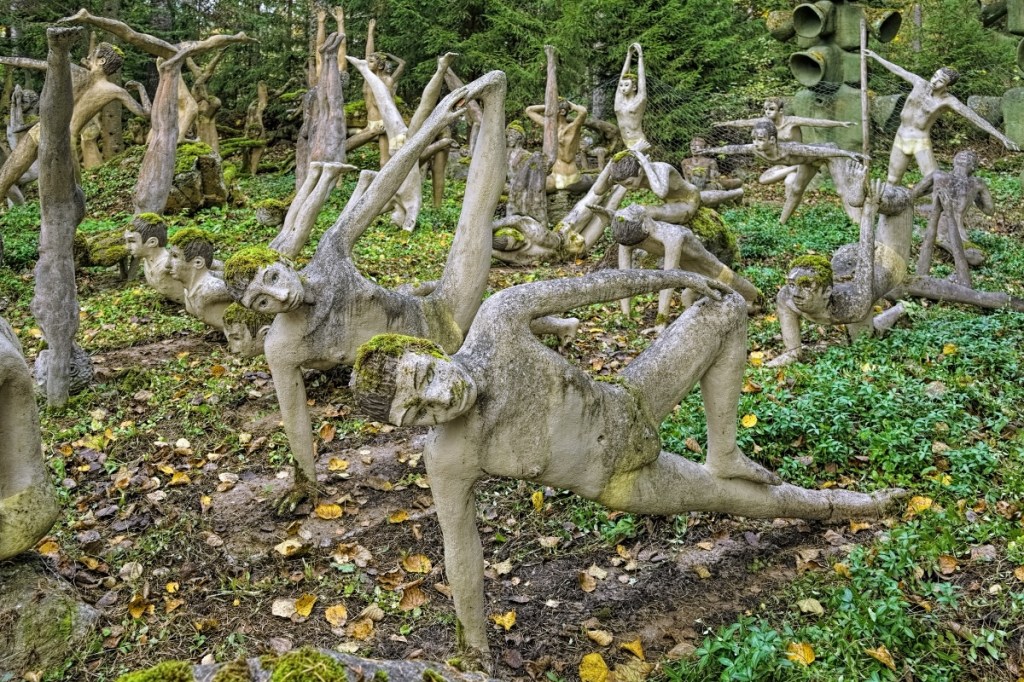 Skulpturen, die Menschen in Yoga-Pose zeigen, in freier Natur fotografiert.