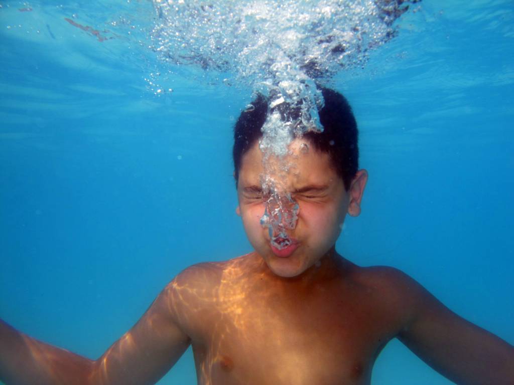 Ein Junge in einem Schwimmbad unter Wasser.