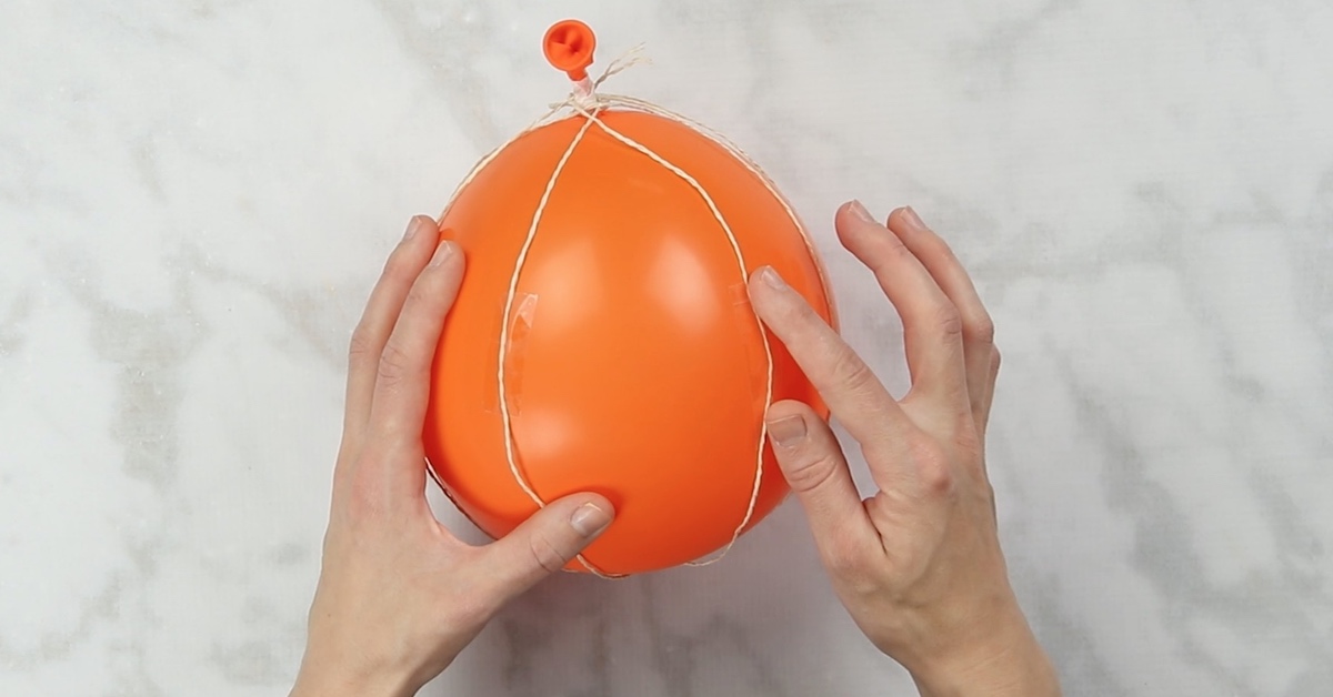 Ein orangefarbener Ballon wird eingeschnürt.