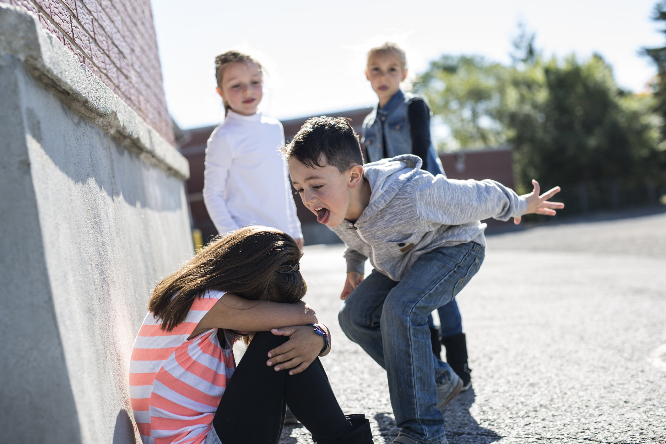 Kinder ärgern ein Mädchen auf dem Schulhof