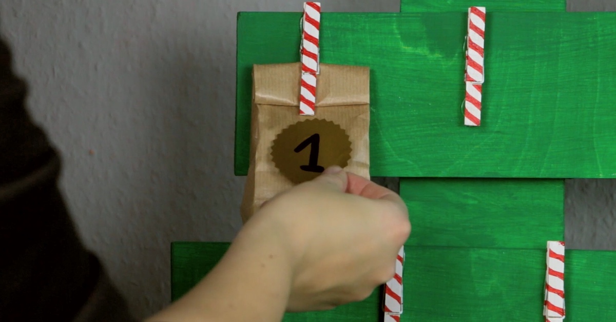 Befülle die Tüten und klemme sie mit den Wäscheklammern an deinen Adventskalender.