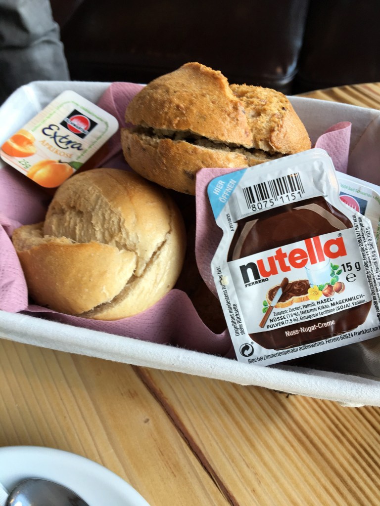 Ein Frühstückskorb mit Brötchen, Nutella und Marmelade.