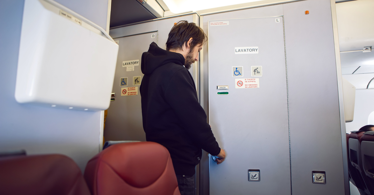 Flugzeugtoilette und ein Mann steht davor.