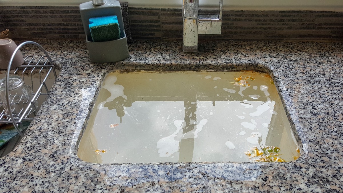 Ein schmutziges Waschbecken in einer Küche wird mit Wasser befüllt.