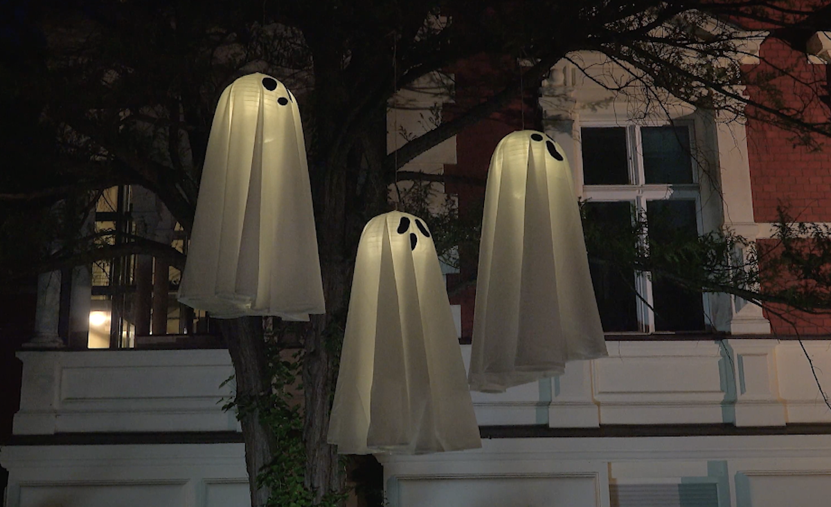 Leuchtende Geisterdeko im Dunkeln vor einem Haus