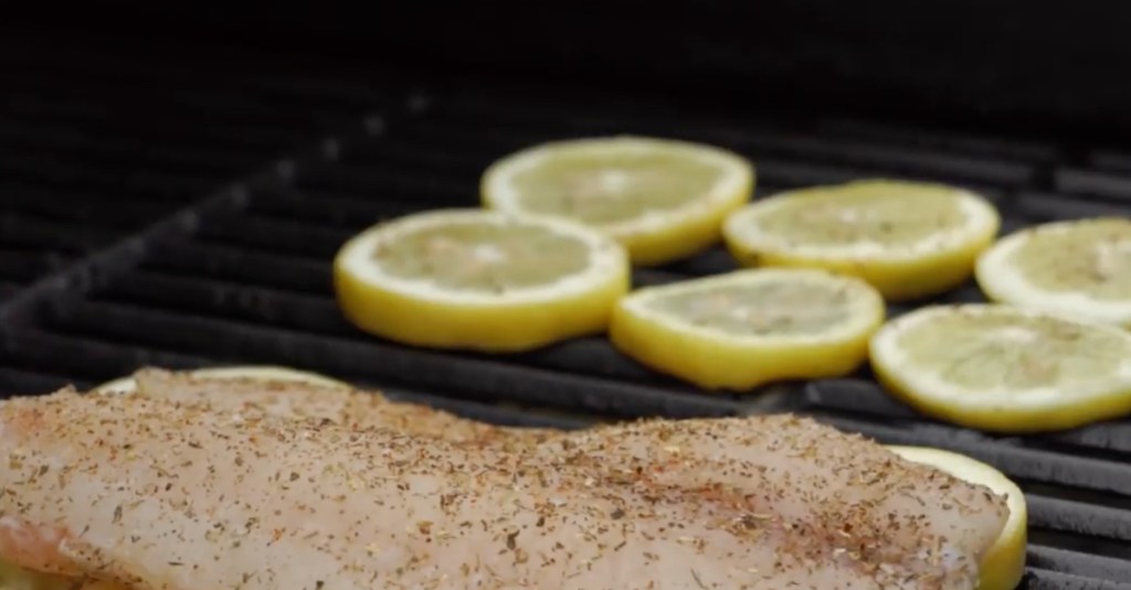 Fisch und Zitronen liegen auf dem Grill.