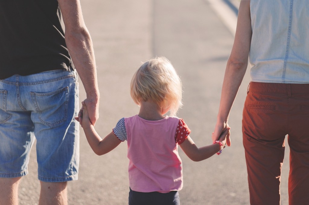 Kleines Mädchen läuft bei Mutter und Vater an den Händen