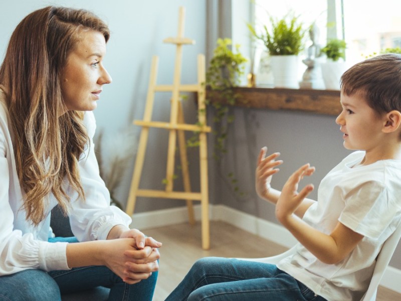 Mutter und Sohn sitzen sich gegenüber und unterhalten sich