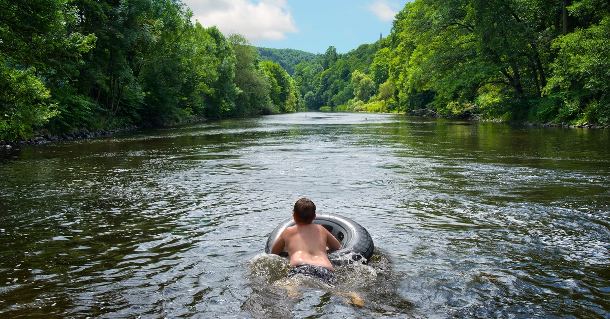 Ein Junge schwimmt auf einem Schwimmreifen im Fluss.