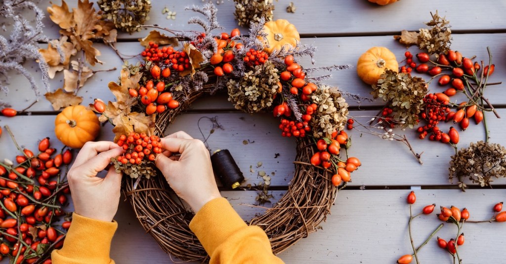 Eine Frau bindet einen Herbst-Kranz.