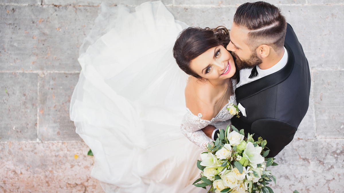 Eine Hochzeitspaar wird von oben fotografiert. Die Braut schaut glücklich nach oben in die Kamera.