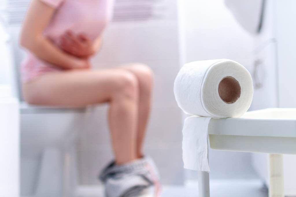 Frau sitzt auf der Toilette.