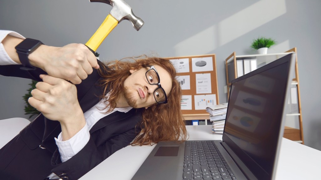 Mann schlägt Computer mit Hammer kaputt.