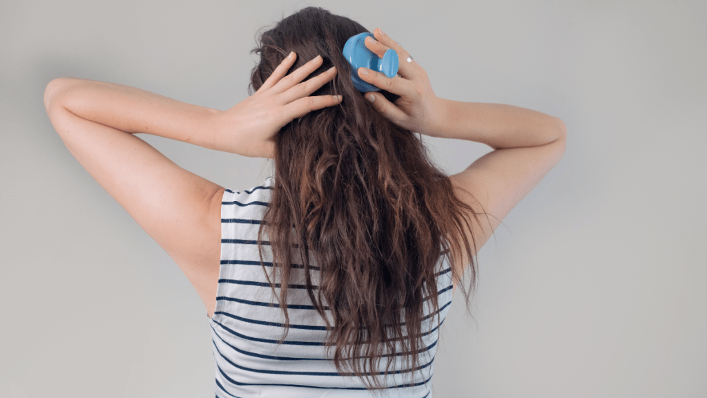 Eine Frau von hinten fotografiert, bürstet ihre langen blonden Haare.