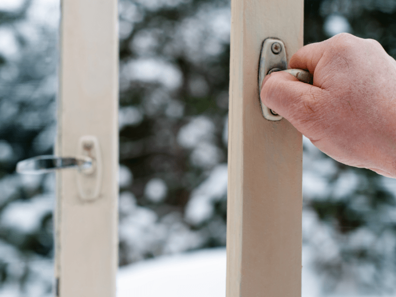 Hände öffnen Fenster im Schnee