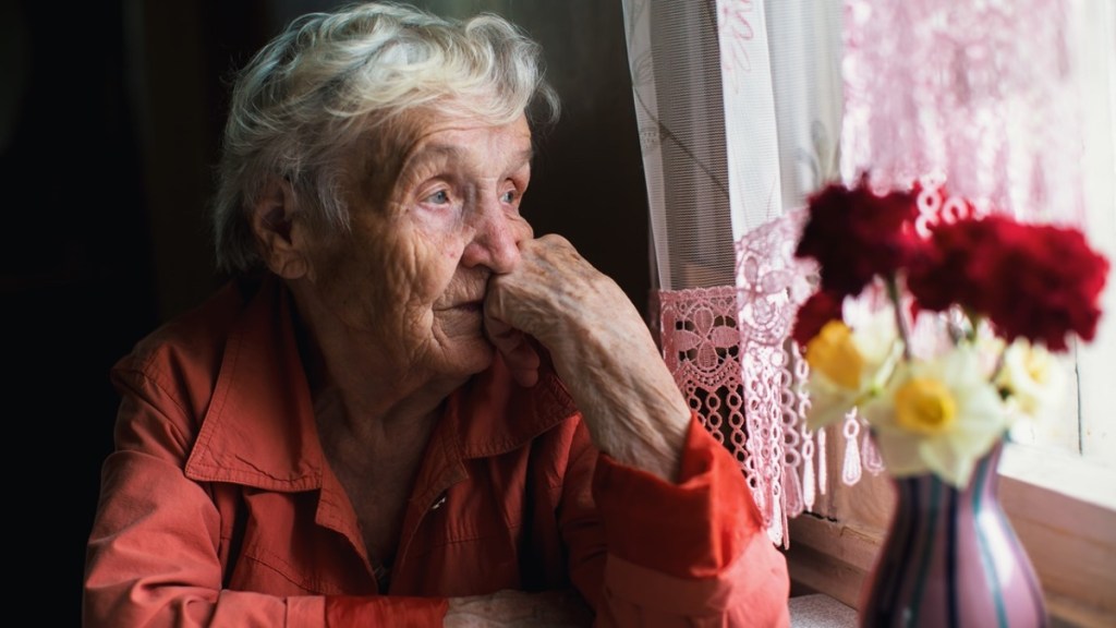 Seniorin sitzt am Fenster